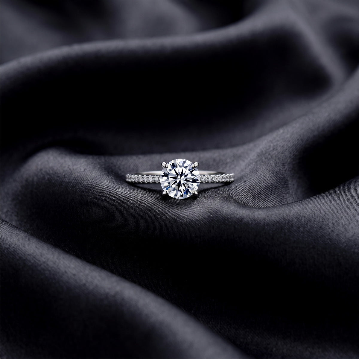 Front view of round brilliant lab grown diamond engagement ring with accent stones on dark black silk