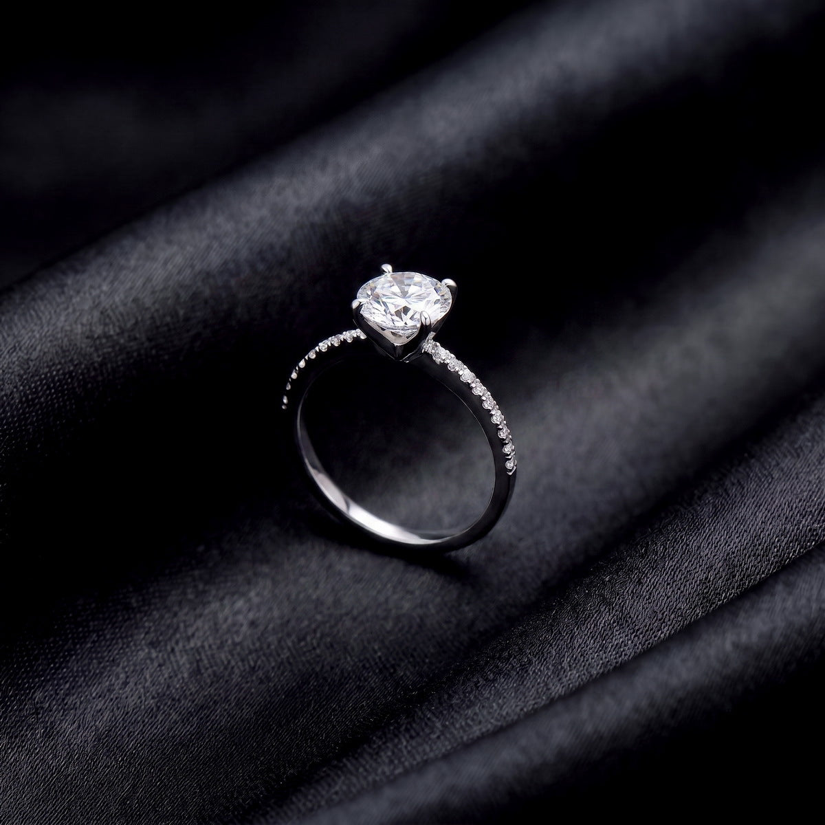 Side profile view showing 4-prong setting and pavé band of lab grown diamond ring on black silk