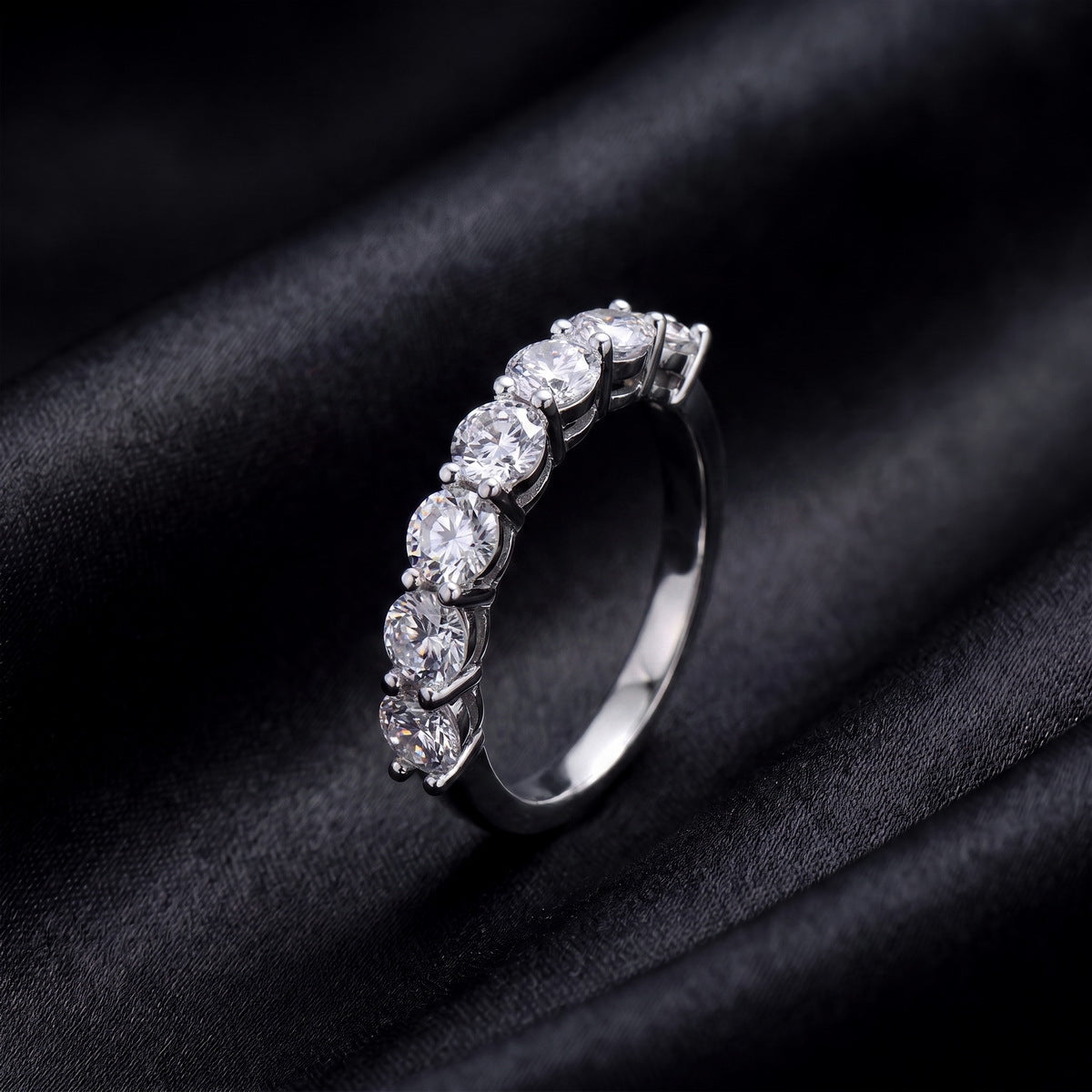 Side profile view showing shared prong setting of 7 stone round lab grown diamond ring on black silk
