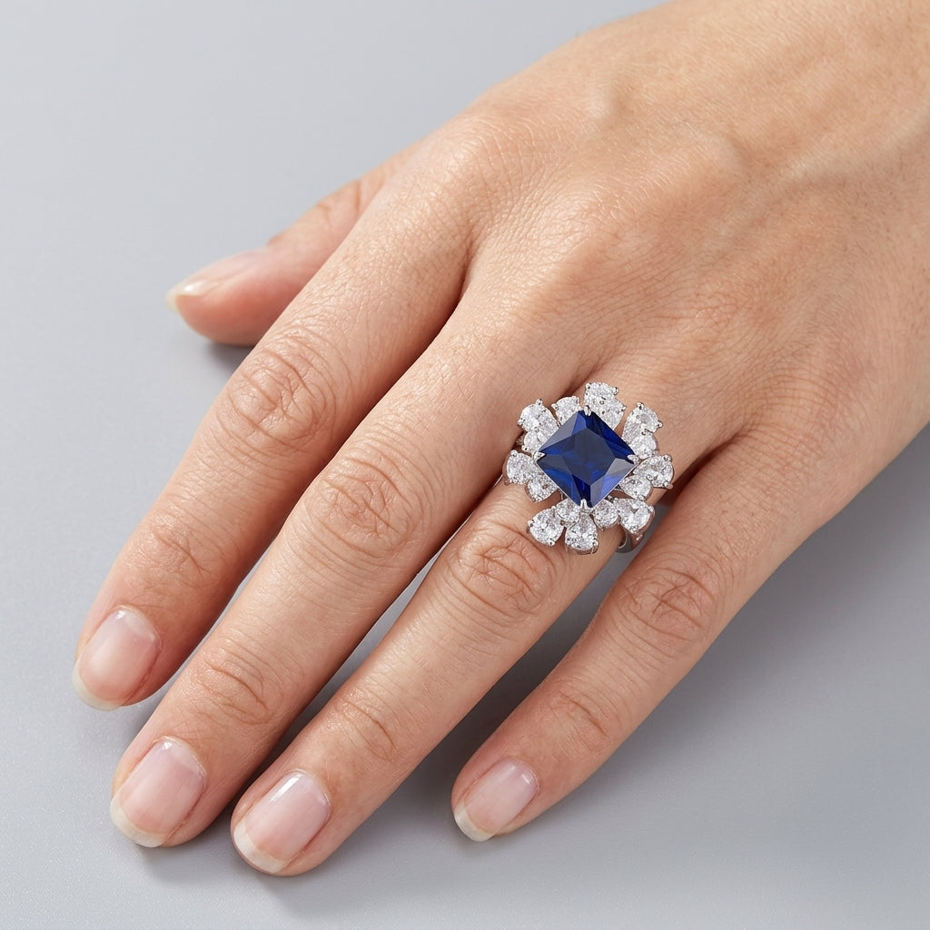 Top-down hand view of a model showcasing a classic asscher sapphire statement cocktail ring on her ring finger.