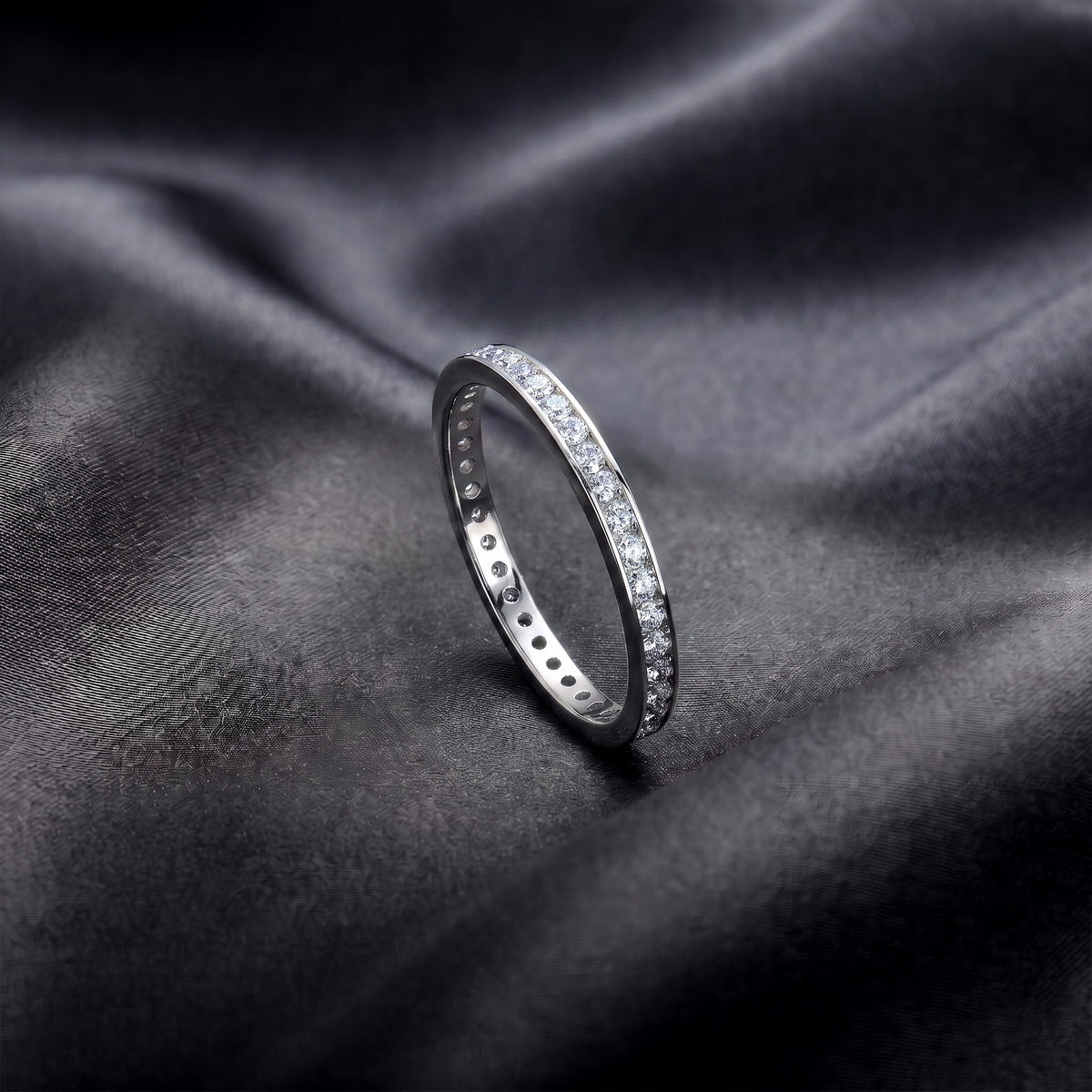 Side profile view of channel set lab grown diamond eternity ring standing on dark silk