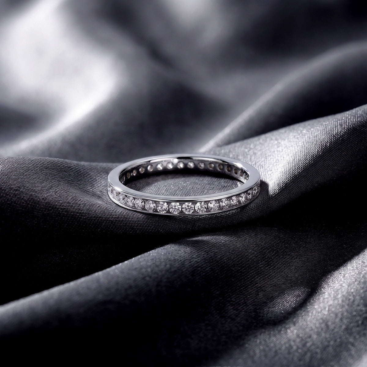 Classic channel set lab grown diamond wedding band resting flat on dark black silk fabric