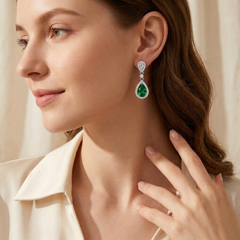 Side profile view of an elegant model wearing classic emerald pear-shaped chandelier drop earrings.