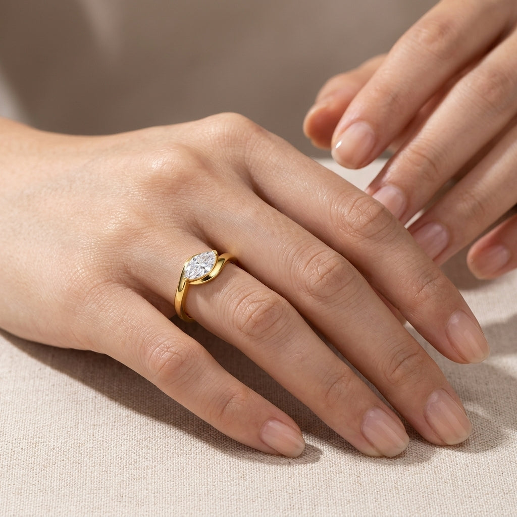 High-end fashion lookbook view of a model gracefully wearing an 18k gold east west marquise moissanite ring.