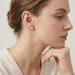 High-end fashion lookbook view of a model elegantly wearing 18k gold puffy heart moissanite stud earrings.
