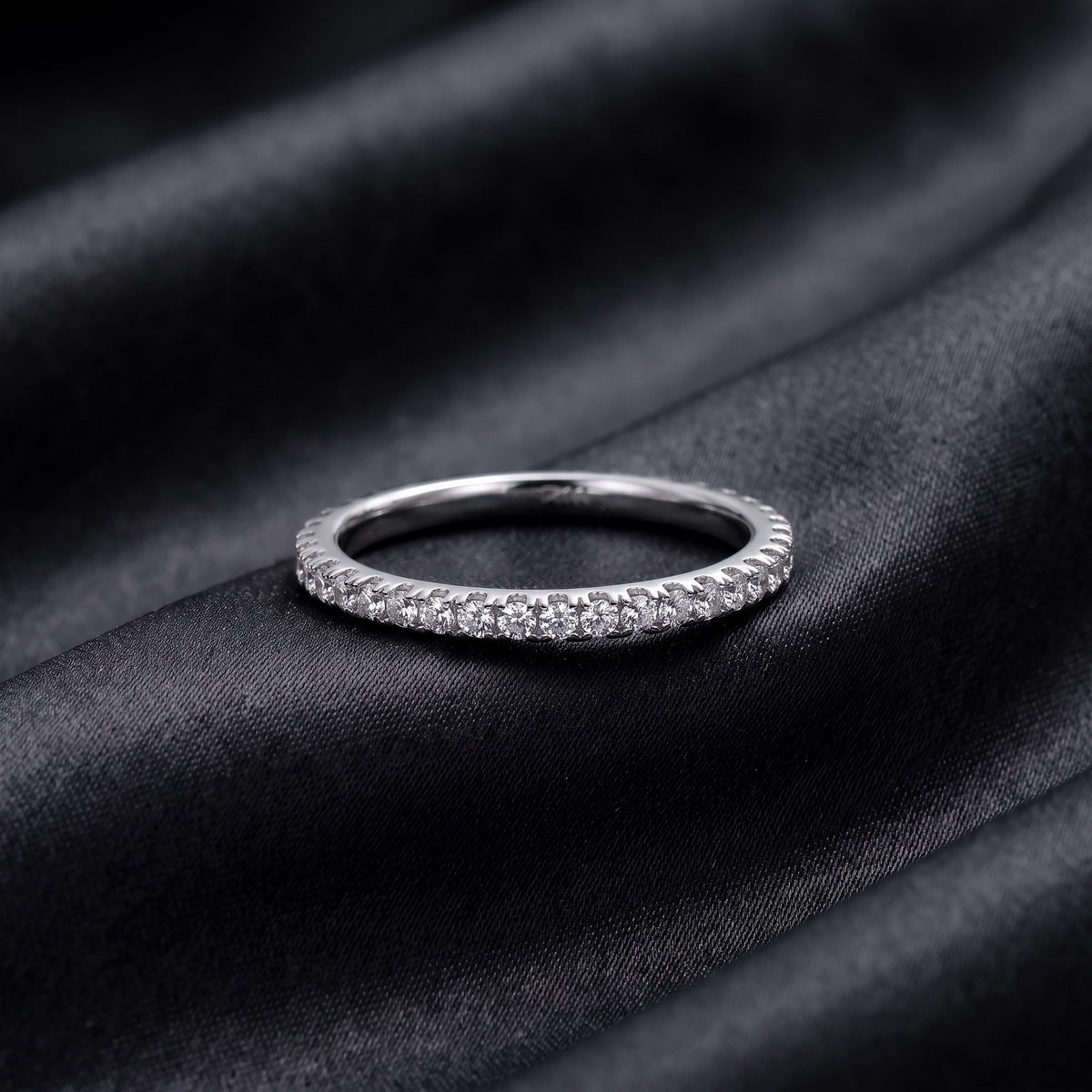 Classic lab grown diamond eternity wedding band resting flat on dark black silk fabric