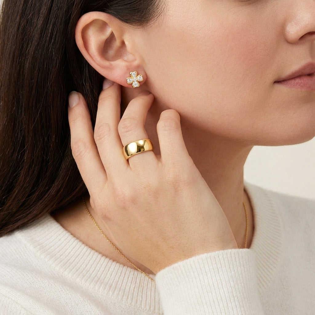 High-end fashion lookbook view of a model showcasing gold moissanite lucky four-leaf clover earrings near her face.
