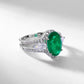 Three-quarter studio product view of a classic oval-cut emerald halo ring casting a crisp gradient shadow.