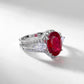 Three-quarter studio product view of a classic oval-cut ruby halo ring casting a crisp gradient shadow.