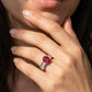 Close-up of a hand wearing a ring with a red gemstone.