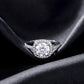 Front view of round cut cushion halo lab grown diamond ring with micro-pavé band resting on dark black silk