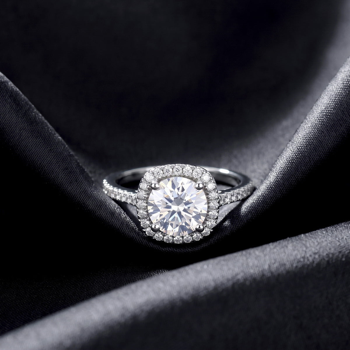 Front view of round cut cushion halo lab grown diamond ring with micro-pavé band resting on dark black silk