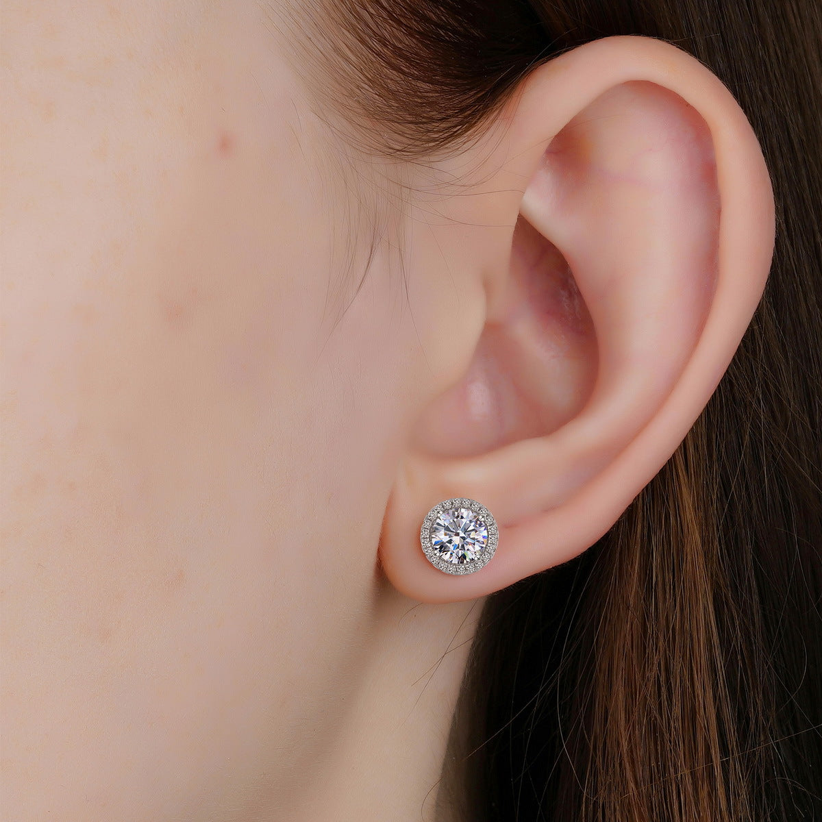Model wearing classic round cut halo lab grown diamond stud earring on earlobe