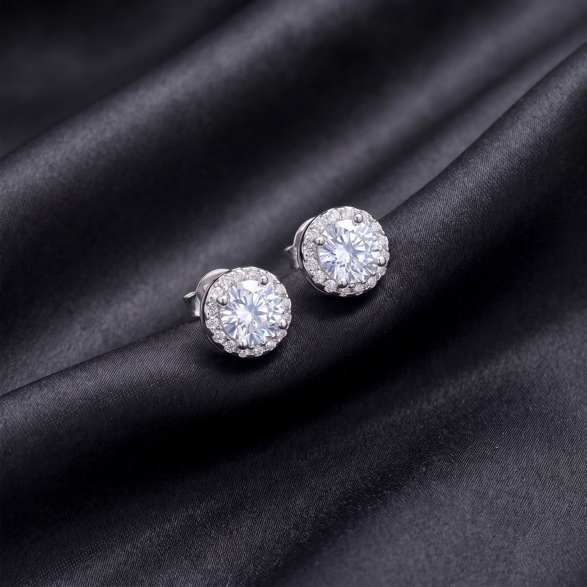 Close up view of classic round brilliant lab grown diamond halo stud earrings on black silk