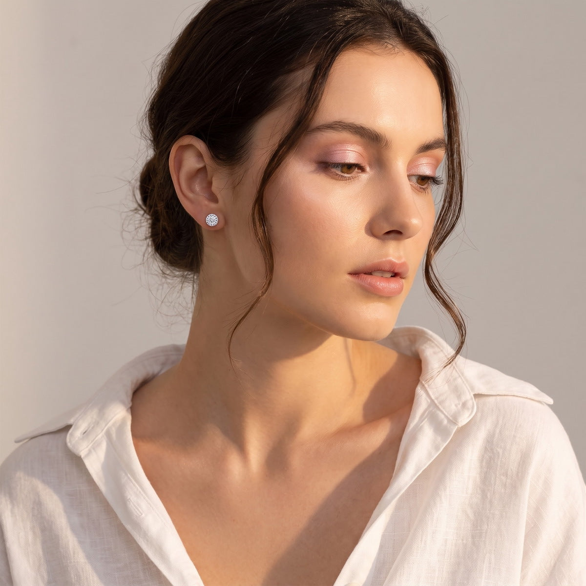 Model wearing classic round cut lab grown diamond halo stud earring on earlobe   