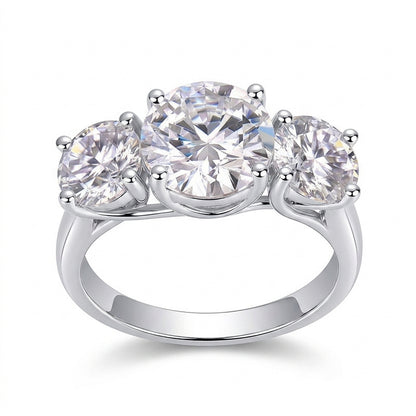 Classic round cut moissanite trilogy three stone engagement ring with plain band on white background.