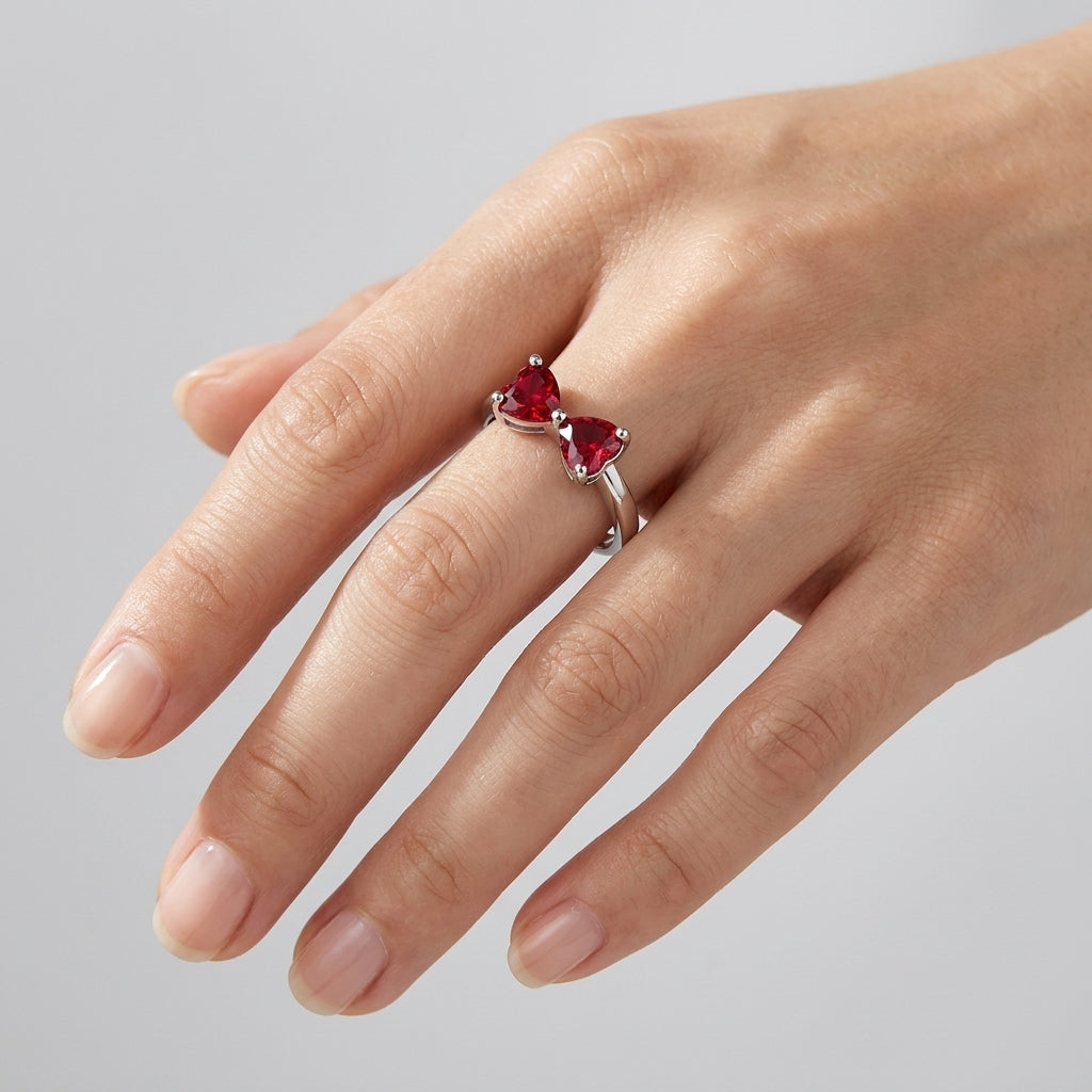 High-angle hand view of a model wearing a classic ruby bow-knot open ring on her index finger.