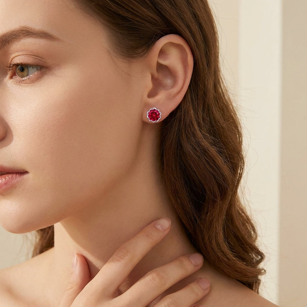Close-up of a woman wearing red gemstone earrings with a neutral background
