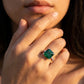 High-angle view of a luxury minimalist square emerald cocktail ring styled on a woman's finger.background