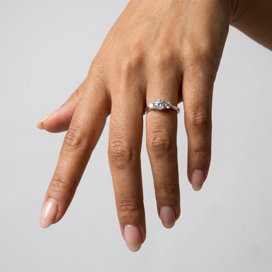 Full hand view of model wearing three-stone past present future engagement ring.