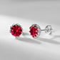 Pair of silver earrings with red gemstones on a light gray background