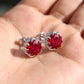 Red gemstone earrings held in a hand