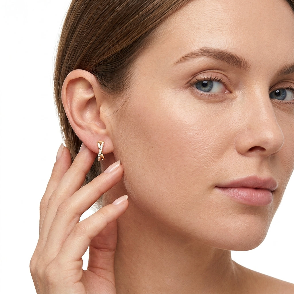 Model wearing gold crisscross X moissanite huggie hoop earrings in a lifestyle portrait.