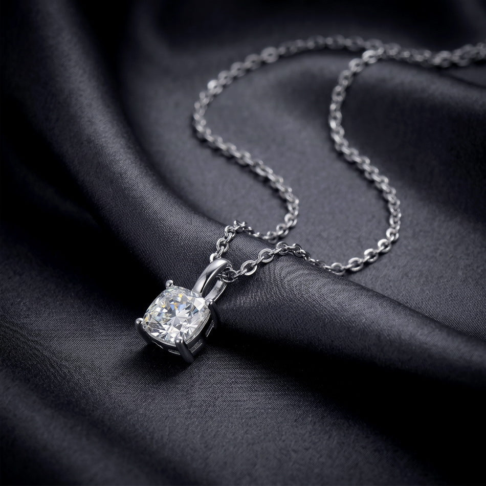 Angled shot of cushion cut lab grown diamond four-prong pendant on dark silk.