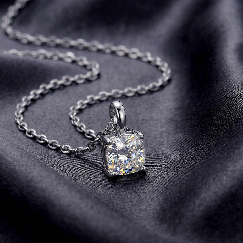Cushion cut lab grown diamond solitaire pendant resting on dark silk fabric.
