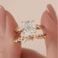 Close-up view of cushion cut moissanite botanical twig ring set held between fingers.