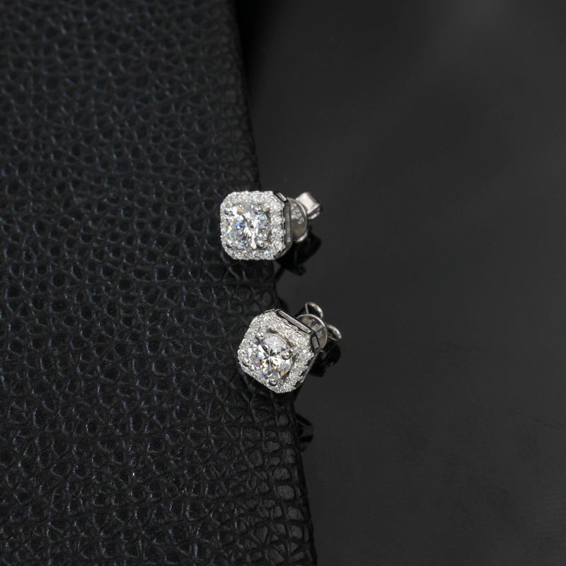 Round diamond cushion halo stud earrings displayed on black textured leather background.