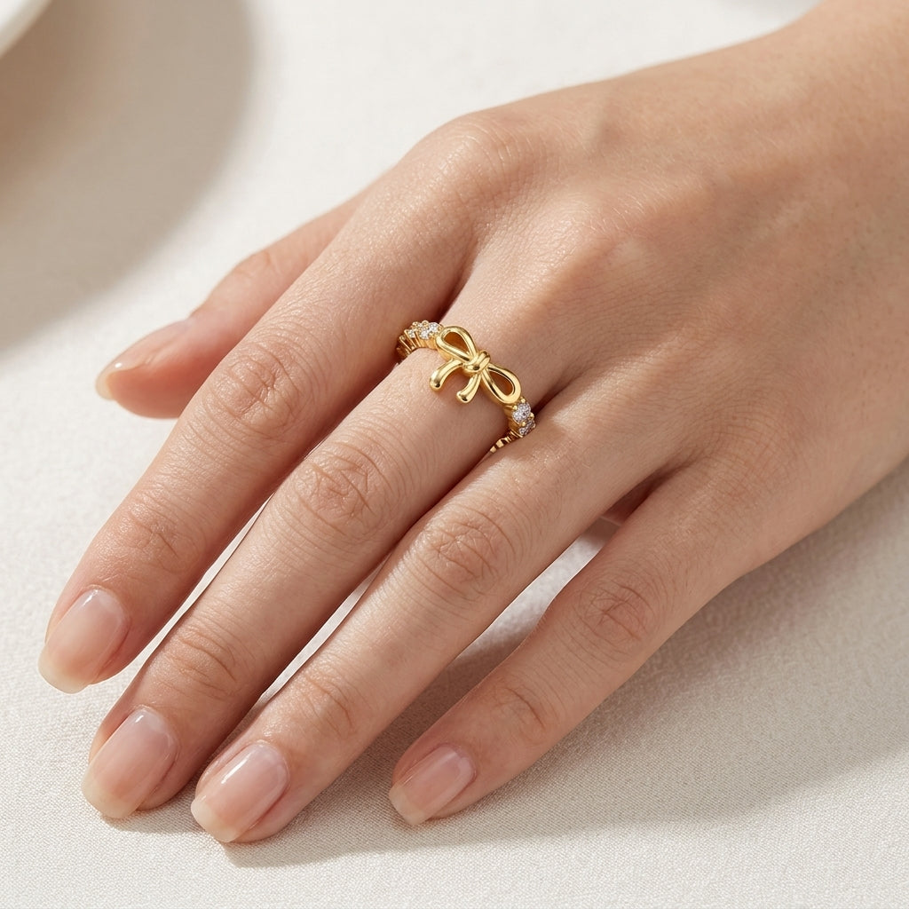 Close-up shot of a woman's hand wearing the delicate gold ribbon bow knot eternity ring.
