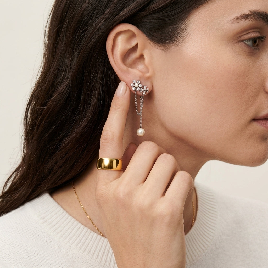 Lifestyle fashion lookbook portrait of a model styling designer gold moondance pearl chain drop earrings near her face.