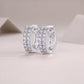 Double row moissanite huggie hoop earrings display on neutral textured background.