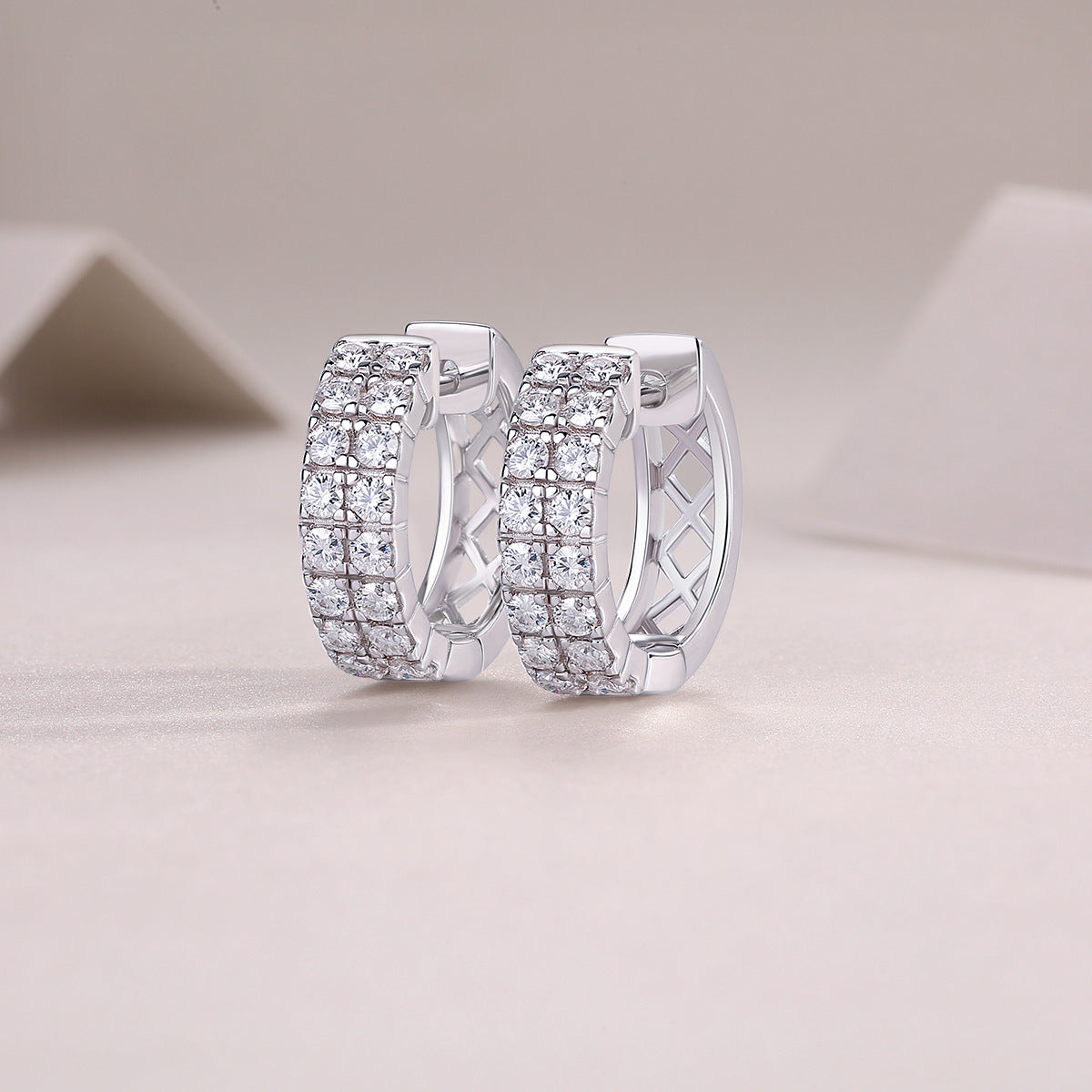 Double row moissanite huggie hoop earrings display on neutral textured background.