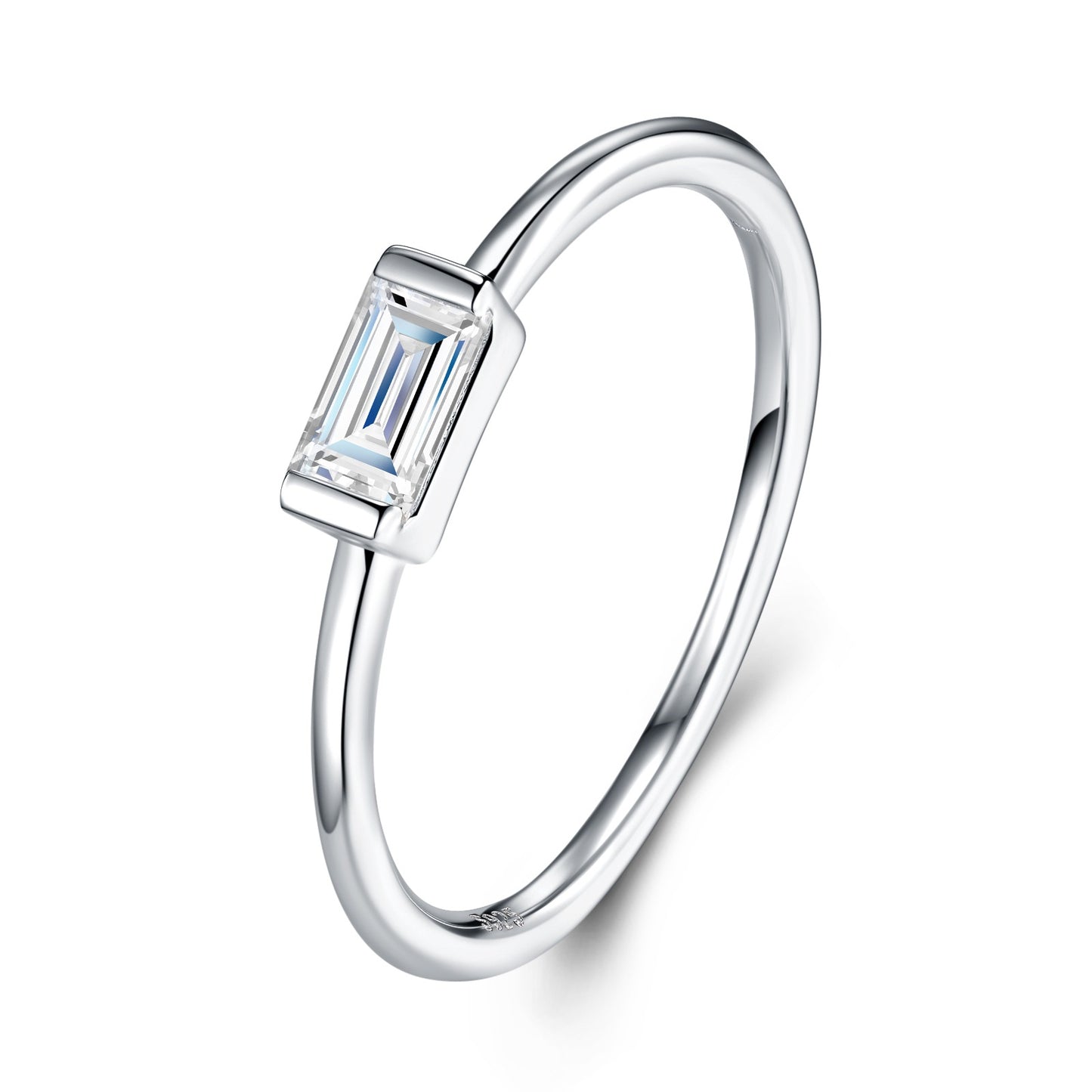 East-West emerald cut moissanite bezel ring with delicate plain silver band on white background.