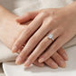 Model showing East-West emerald cut moissanite bezel ring on hand in warm natural light.