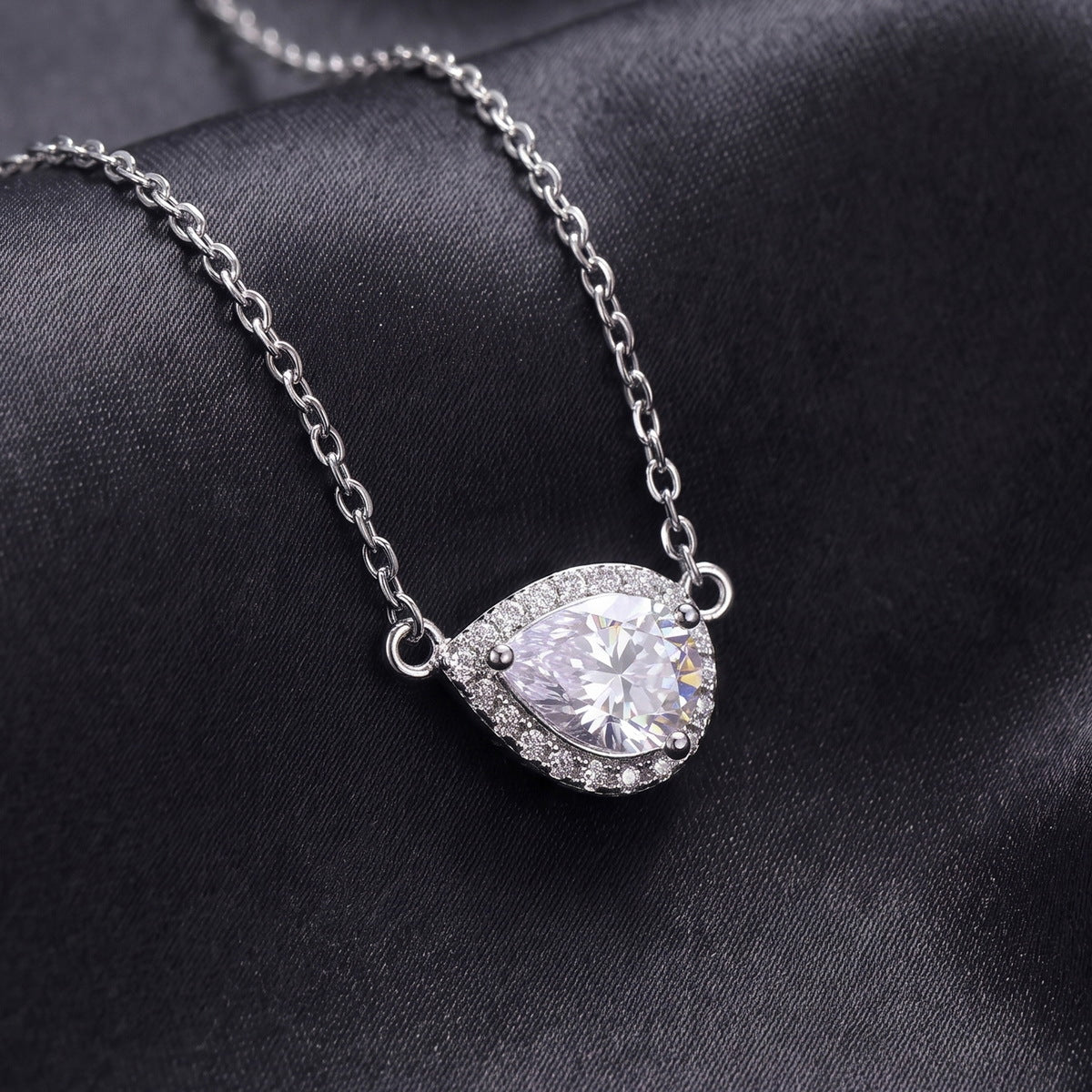 Close up view showing micro pave halo and horizontal pear cut moissanite pendant   