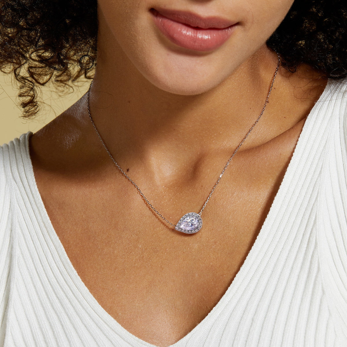 Model wearing east-west pear cut moissanite halo pendant necklace on neck   