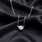 East-west pear cut moissanite halo pendant necklace resting on black silk fabric   
