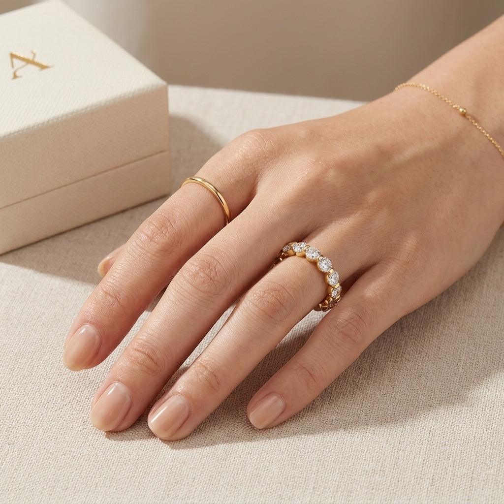Closeup lookbook view of a model's hand next to a jewelry box, wearing an effortless luxury d vvs1 moissanite anniversary ring in gold.