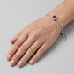 Top-down hand view of a model wearing an elegant cushion-cut ruby halo tennis bracelet resting on a smooth backdrop.