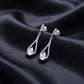 Angled side view of pear cut lab grown diamond teardrop drop earrings on black silk