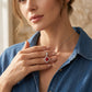 Close-up lifestyle view of a model showcasing the elegant ruby four-leaf pendant necklace styled with a blue denim shirt.