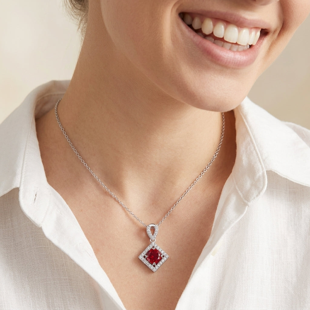 Editorial portrait view of a smiling model wearing an elegant ruby geometric halo necklace with a casual white shirt.