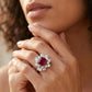 Close-up lifestyle view of a moody model leaning on her hand, displaying an elegant ruby sunflower halo engagement ring.