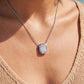 Model wearing emerald cut diamond bezel-prong solitaire pendant necklace.