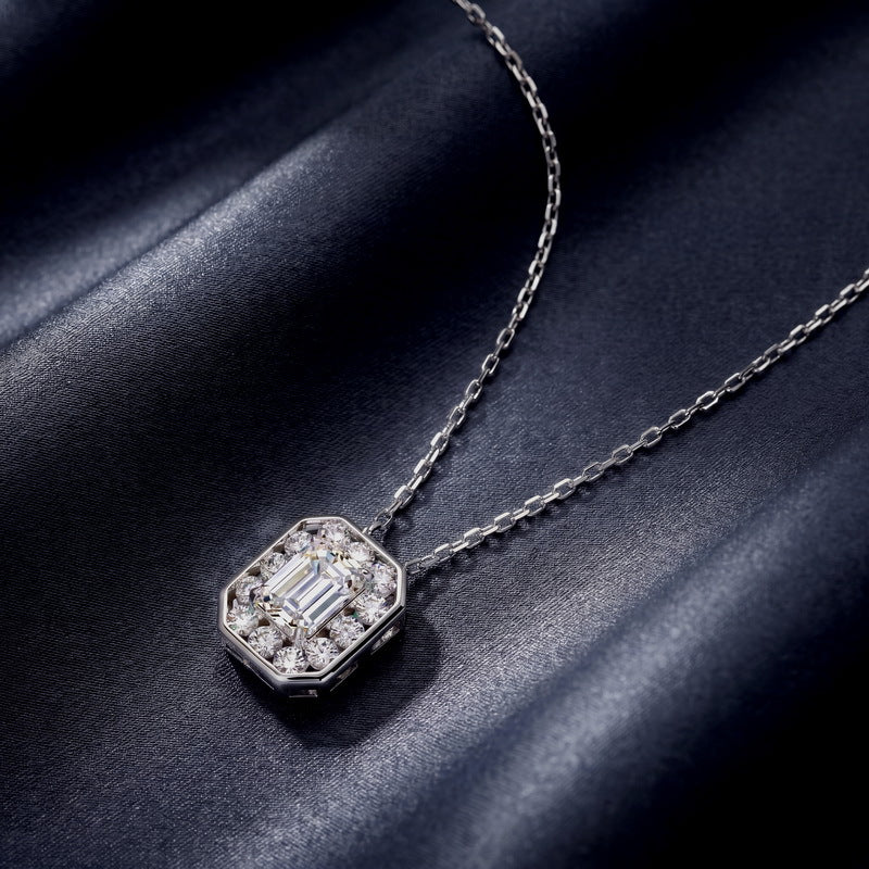 Emerald cut diamond octagonal halo bezel pendant displayed on navy blue background.