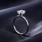 Side perspective shot of emerald cut hidden halo solitaire ring resting on dark silk.