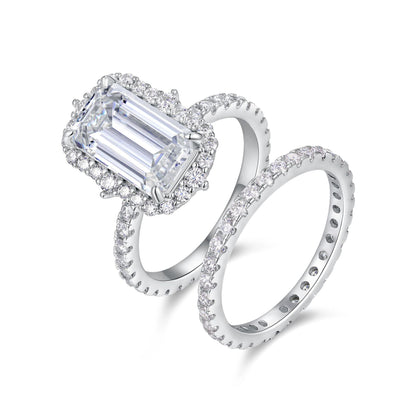 Emerald cut moissanite halo engagement ring with pave stacking wedding band on white background.